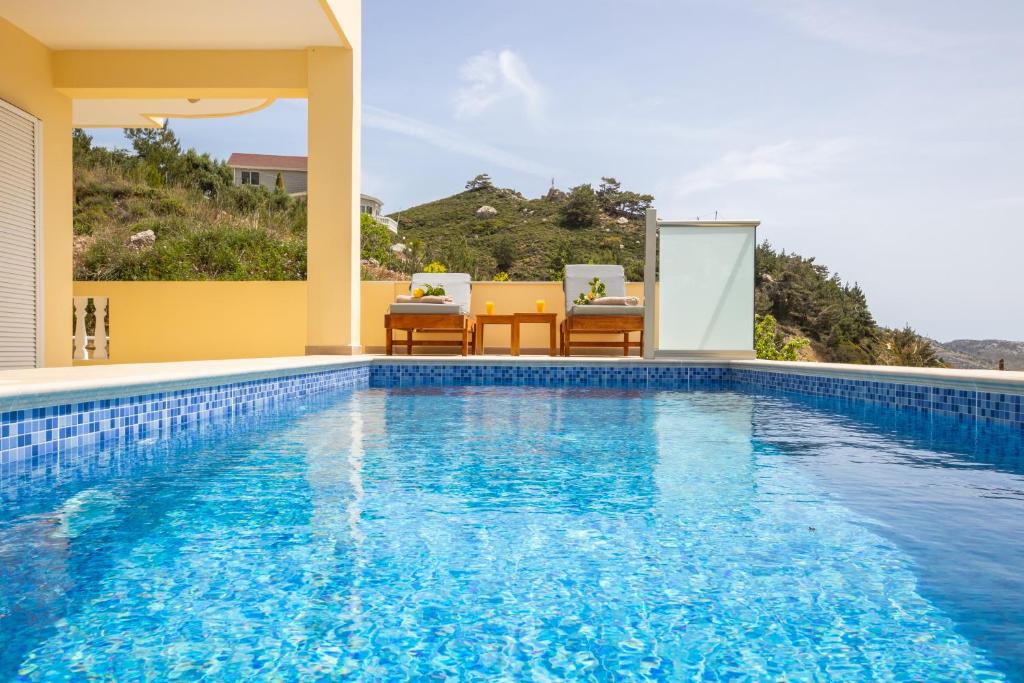 a pool with a table and chairs next to a house at Karpathos View Villa in Karpathos
