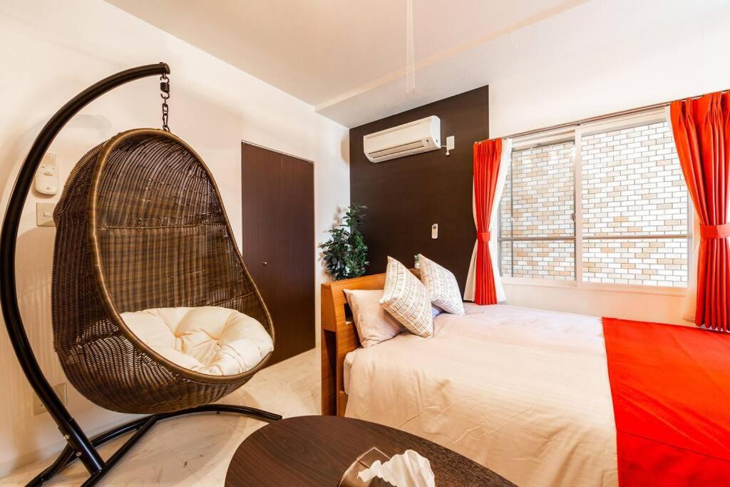 une chambre avec une chaise en osier à côté d'un lit dans l'établissement ORANGE, à Sapporo