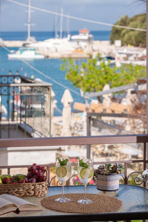 a table with two wine glasses and a basket of fruit at Esperides Studios in Syvota