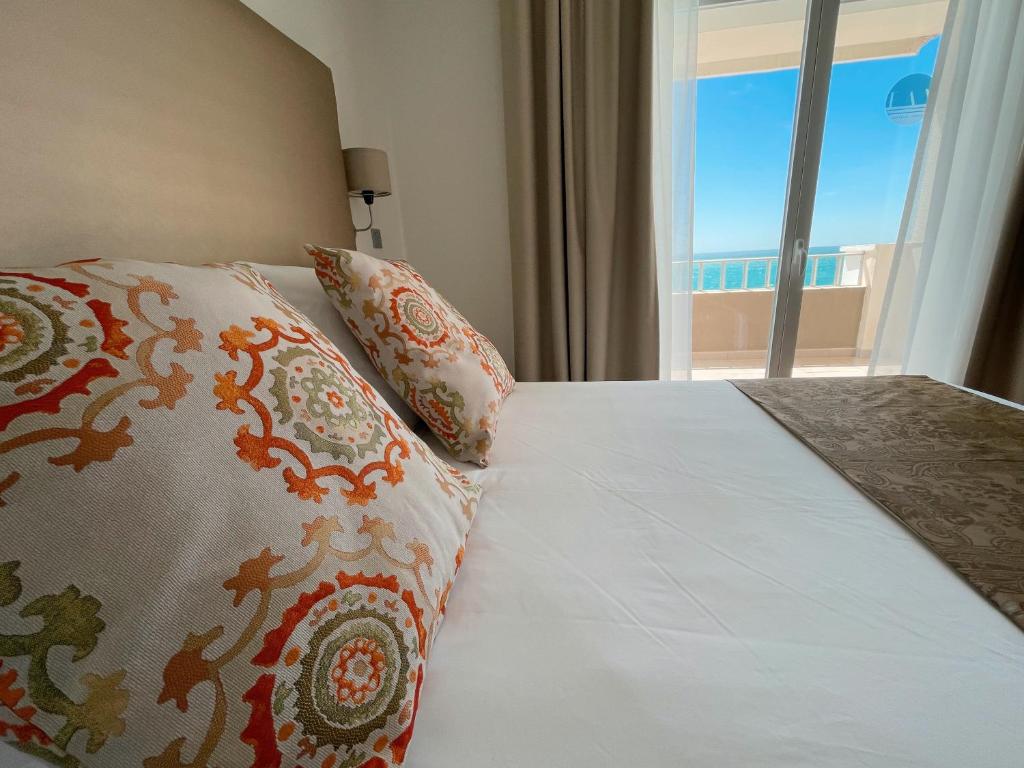 a bedroom with a bed with pillows and a window at FAY Victoria Beach in Rincón de la Victoria