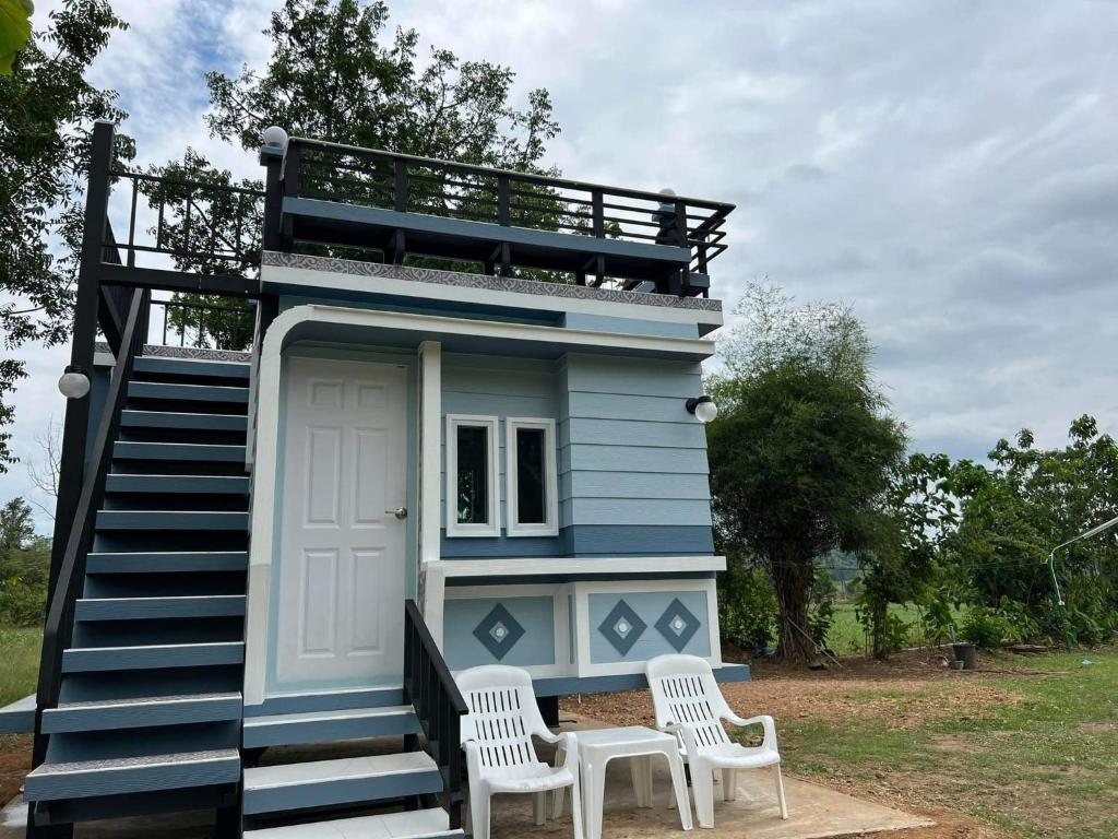 a small blue house with two white chairs in front of it at ภูผาม่านห่มดาวแคมป์ in Ban Huai Hai