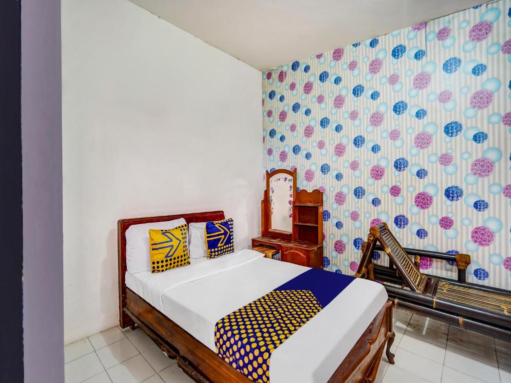 - une chambre avec un lit dans une pièce avec du papier peint dans l'établissement OYO Homes 91103 Syariah Desa Wisata Lembah Gunung Tumpeng, à Sumberwaras
