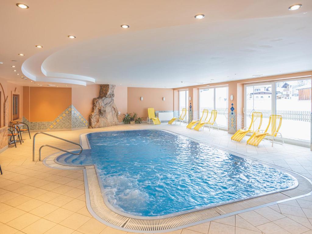 una gran piscina en una habitación de hotel con sillas amarillas en Hotel Styrolerhof en Steeg