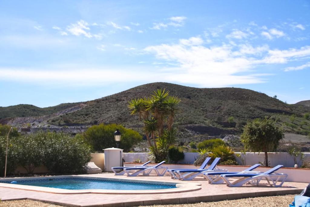 a group of chairs and a swimming pool with a mountain at Villa Marhaba in Arboleas