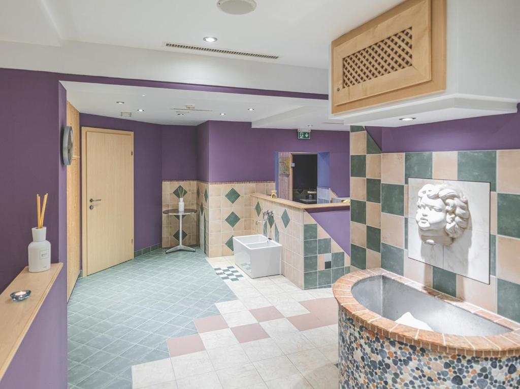 a bathroom with purple walls and a tub at Hotel Styrolerhof in Steeg