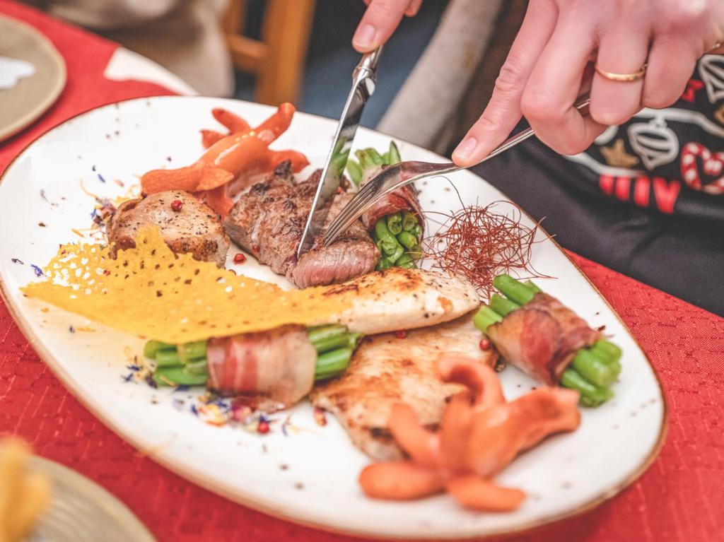 a person cutting a plate of food with a fork and knife at Hotel Styrolerhof in Steeg