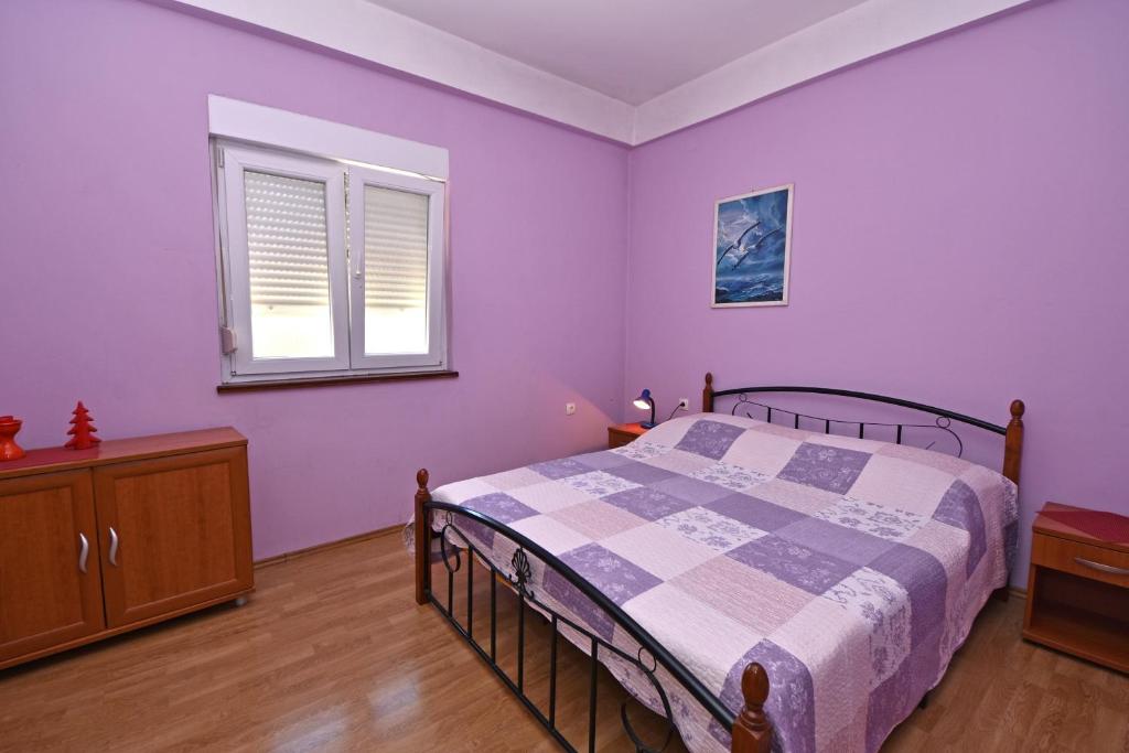 a bedroom with purple walls and a bed and a window at Apartment Meri- near the Zadar main bus station in Zadar