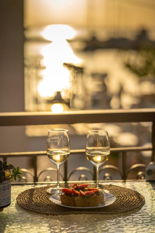 a table with two wine glasses and a plate of food at Esperides Studios in Syvota