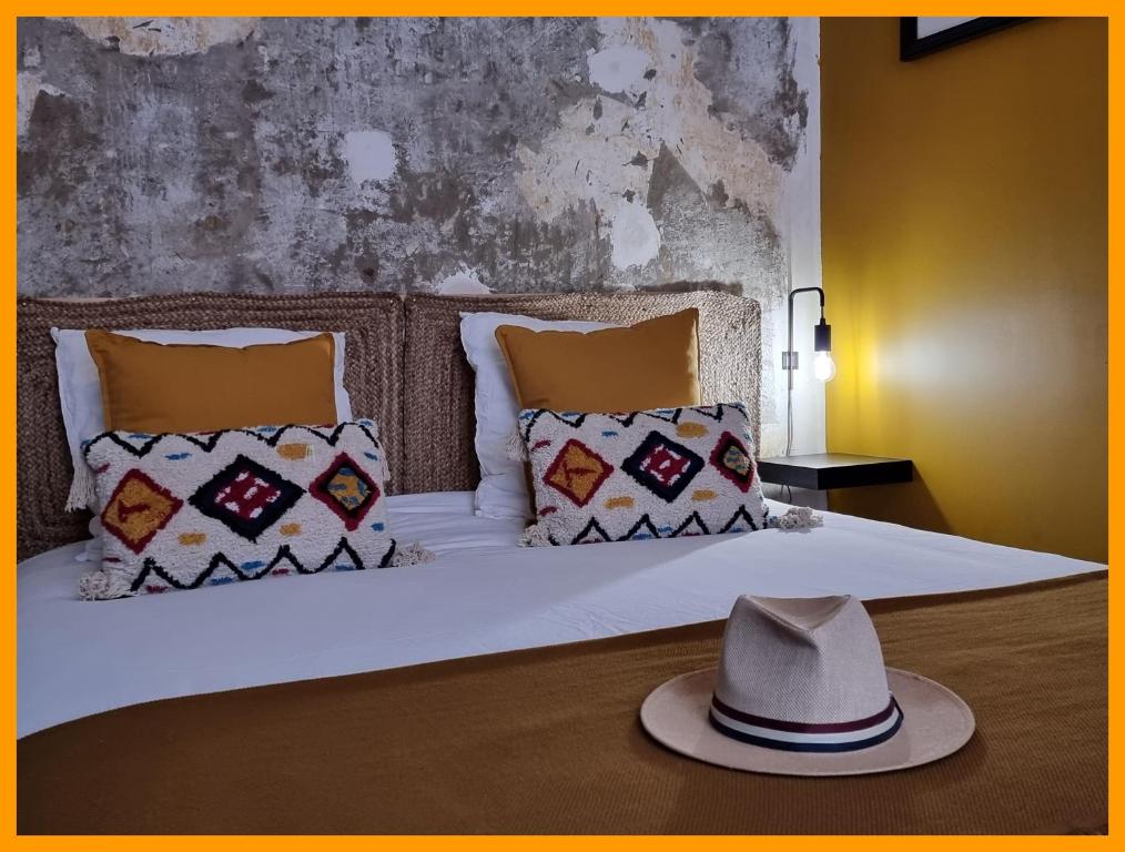 um chapéu em cima de uma cama com almofadas em Gîtes du petit familistère Landrecies em Guise