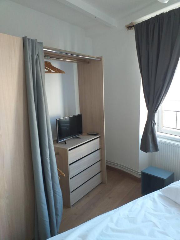 a bedroom with a bed and a dresser with a television at Maison de ville in Vic-le-Comte