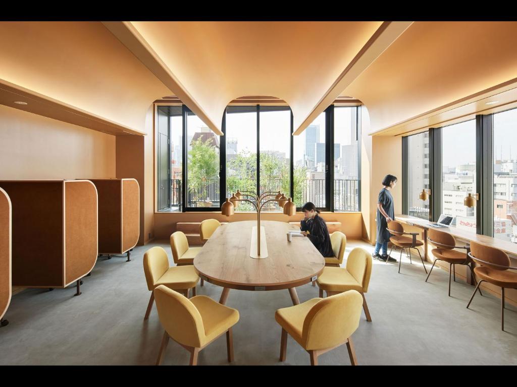 een kamer met een tafel, stoelen en ramen bij 9h nine hours woman Shinjuku in Tokyo