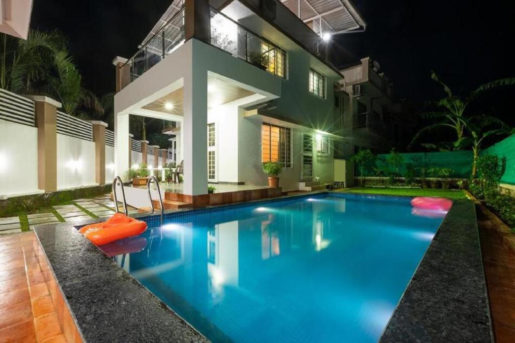 een zwembad voor een huis 's nachts bij Auriga Mansion House in Lonavala