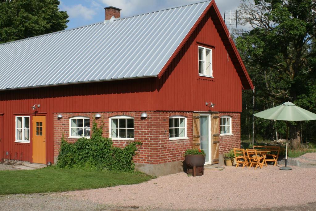 a red barn with a table and chairs and an umbrella at Askebo Brygghus in Gislaved