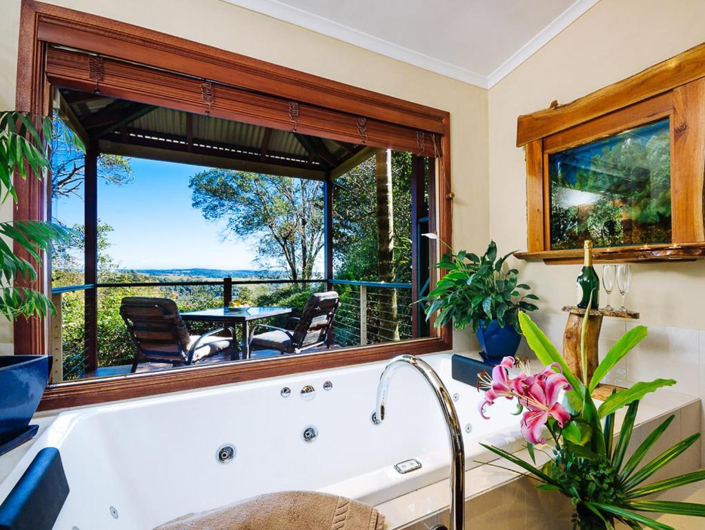 una vasca da bagno in una cucina con una grande finestra di Lillypilly's Cottages & Day Spa a Maleny