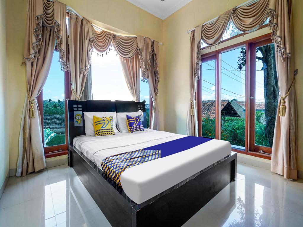 a bedroom with a bed in front of a window at OYO Homes 91156 Eco Tourism Big Farmer Desa Kertawangi Syariah in Lembang
