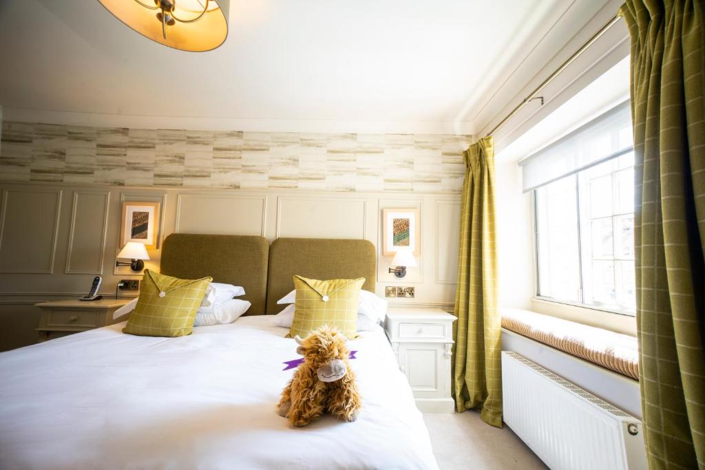 a teddy bear sitting on a bed in a bedroom at Feversham Arms Hotel & Verbena Spa in Helmsley