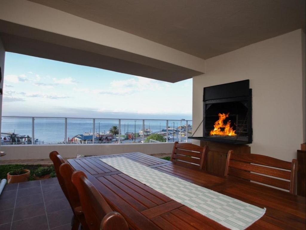 a dining room with a fireplace and a table with chairs at Go2Boa Luxury Apartment in Mossel Bay