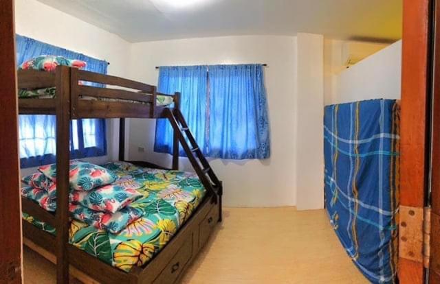 sypialnia z łóżkiem piętrowym i niebieskimi zasłonami w obiekcie Deluxe Villa Leah Natural Hotspring Resort w mieście Calamba