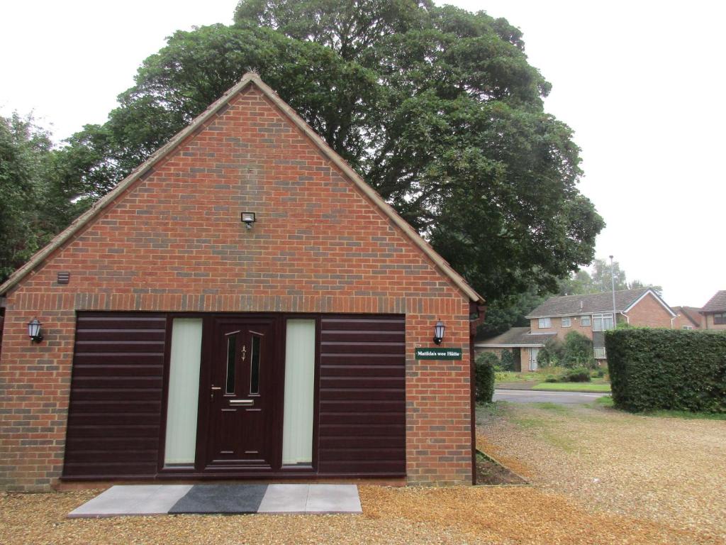 a small brick building with a black garage door at Matilda's wee Hutte in Daventry
