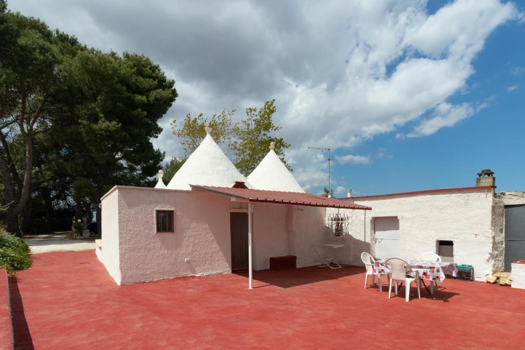 ein weißes Gebäude mit Tischen und Stühlen auf einer Terrasse in der Unterkunft Trulli da Rosy in Martina Franca