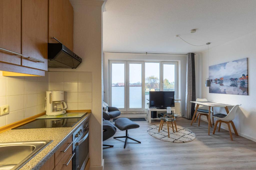 a kitchen with a living room and a table with chairs at Haus Knechtsand, Whg 447 in Duhnen