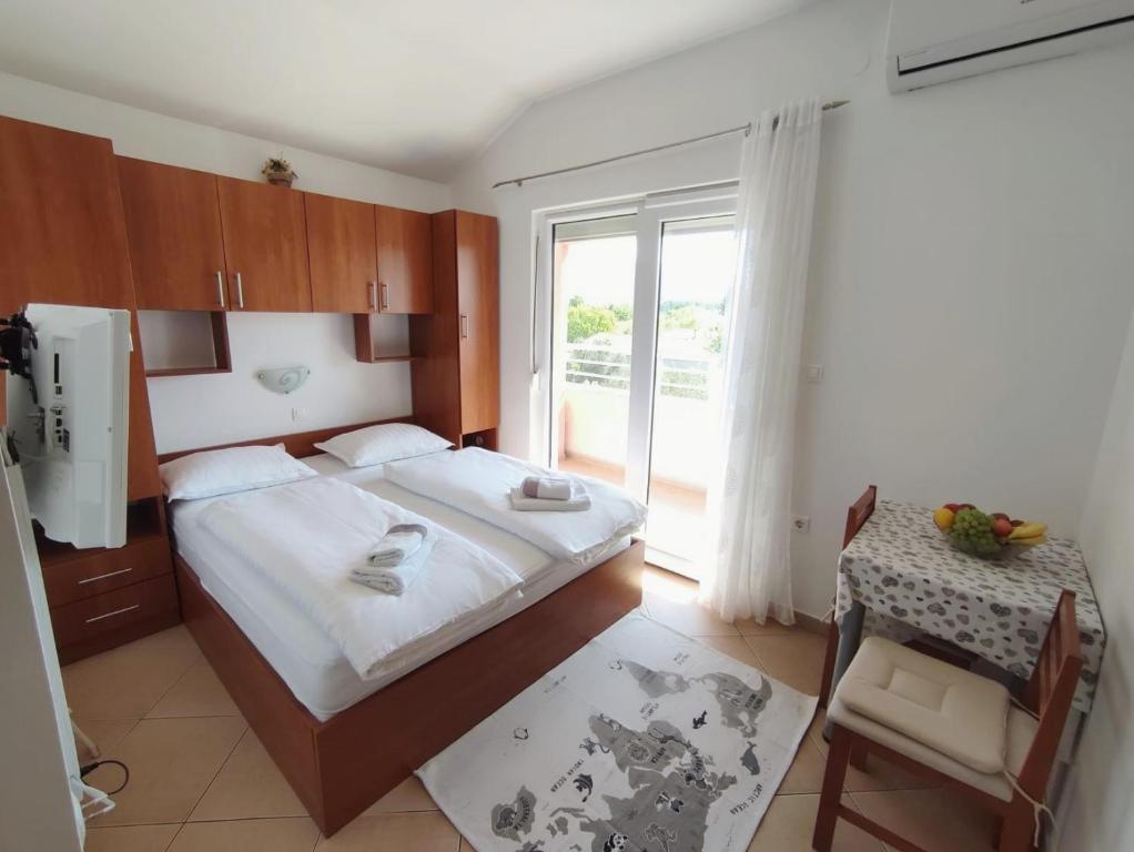 a bedroom with a bed and a table and a window at Apartments Marta in Seline