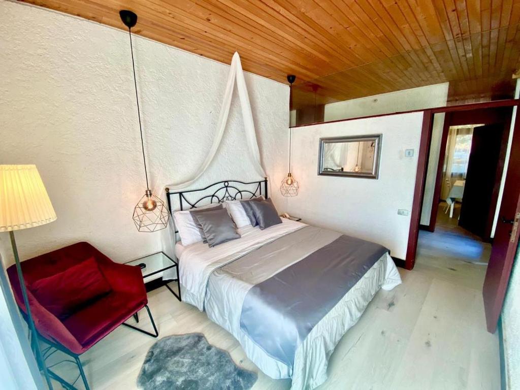een slaapkamer met een bed en een rode stoel bij Appartamento immerso nel verde a soli 10 minuti dal centro di Trento Parte di una villa in Trento