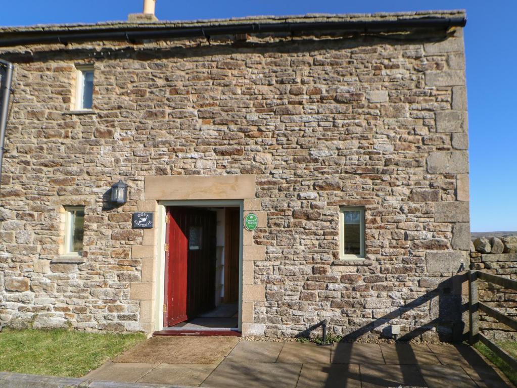 un edificio de ladrillo con puerta roja en Dove Cottage, en Hexham