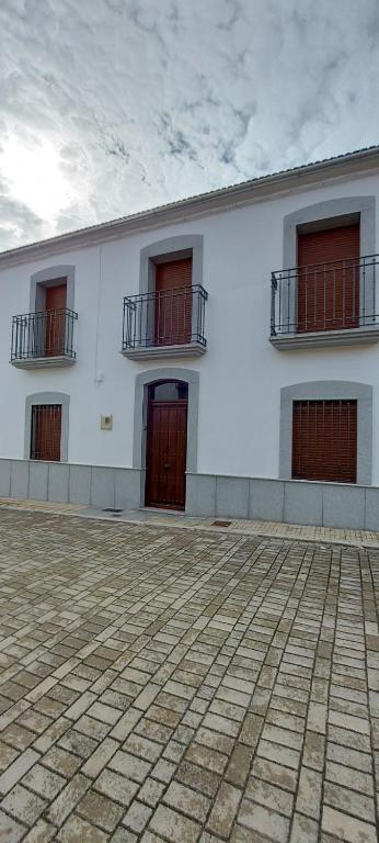 - un bâtiment blanc avec des portes et des fenêtres rouges dans l'établissement Casa Los Tiznaos, à Torrecampo