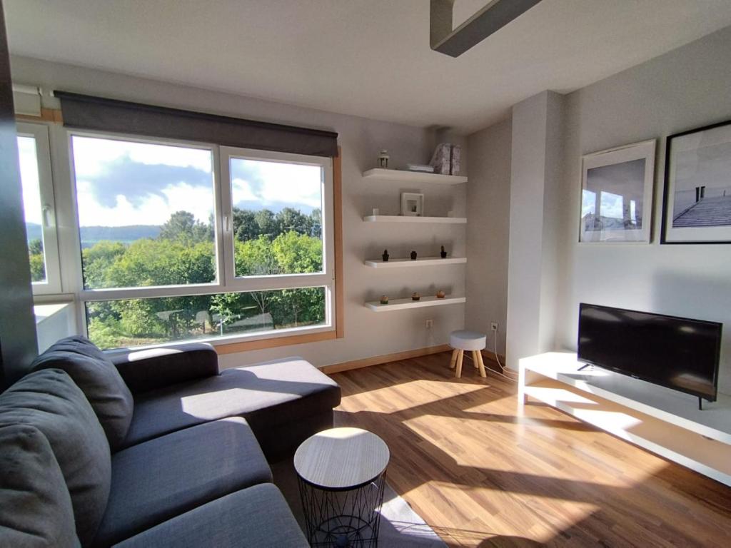 uma sala de estar com um sofá e uma grande janela em Apartamentos Descubre Rías Baixas em Catoira