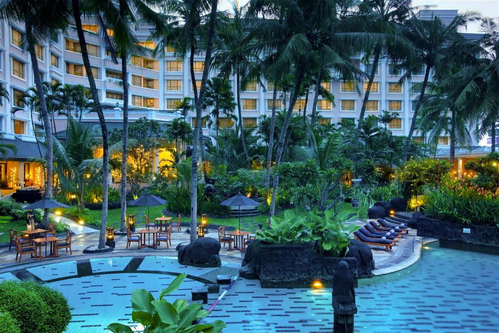 um pátio do hotel com piscina, mesas e cadeiras em Melia Purosani Yogyakarta em Yogyakarta