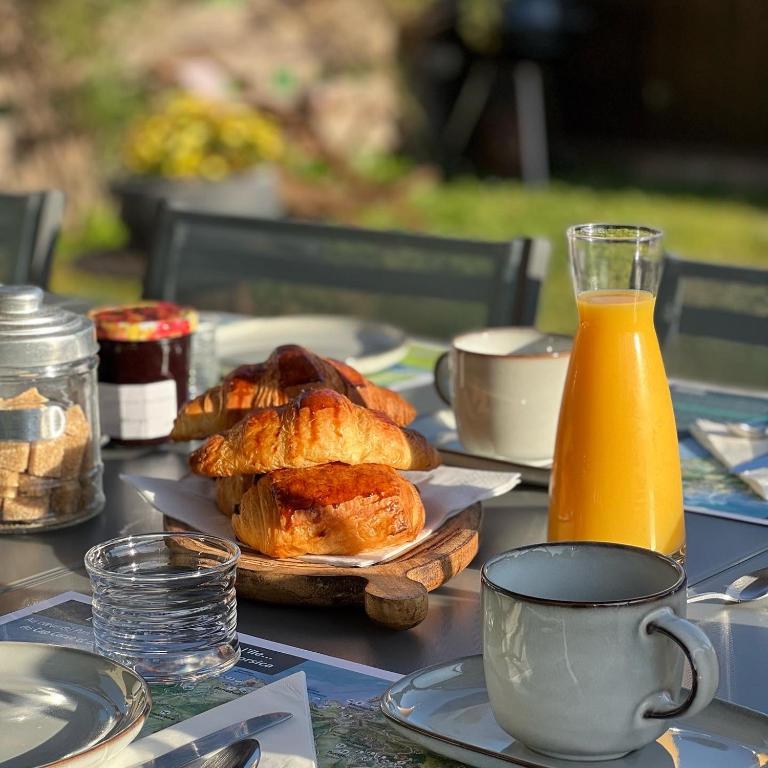 a table with a plate of pastries and a jug of orange juice at Les 5 Arches in Sisco