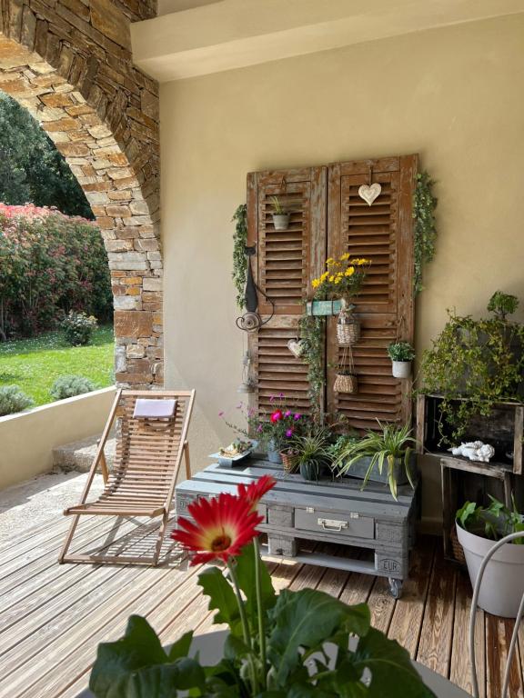 a patio with a chair and flowers and a shutter at Les 5 Arches in Sisco