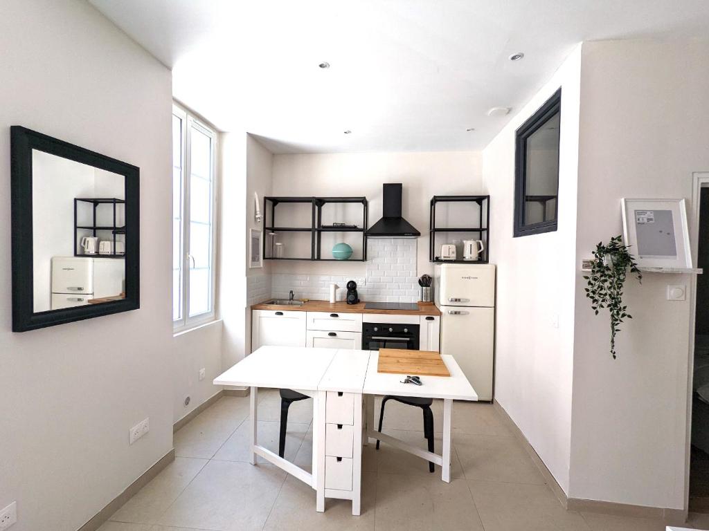 cocina con mesa blanca y nevera blanca en Charmant Appartement en Hypercentre, en Toulouse