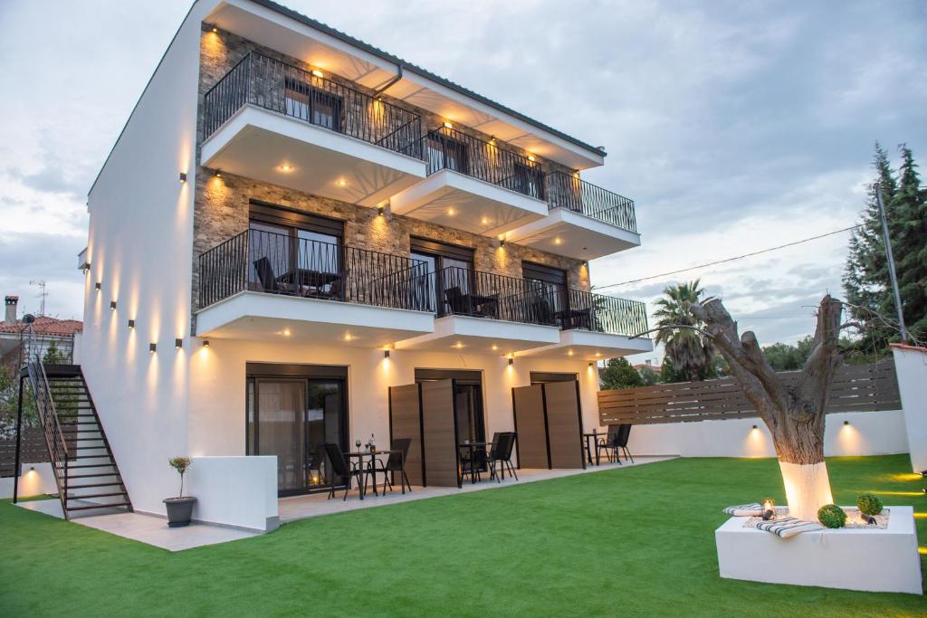 uma casa com um relvado verde em frente em Alios Gaia - Seaside Apartments em Nikiti