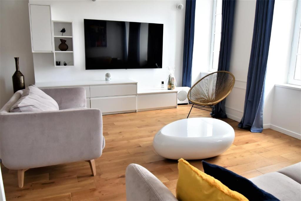 a living room with a tv and a couch and a table at La Maison du Quai Triplex de charme 4 étoiles en hyper centre avec SPA in Landerneau