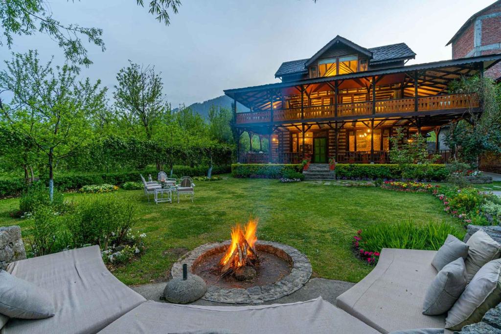 a house with a fire pit in the yard at StayVista at The Kathguni House in Manāli