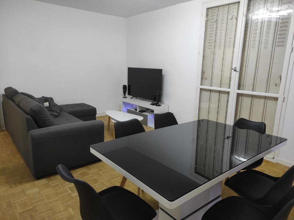een woonkamer met een zwarte tafel en stoelen bij Appartement 70m² Pierrelatte Cosy, NETFLIX+WIFI in Pierrelatte