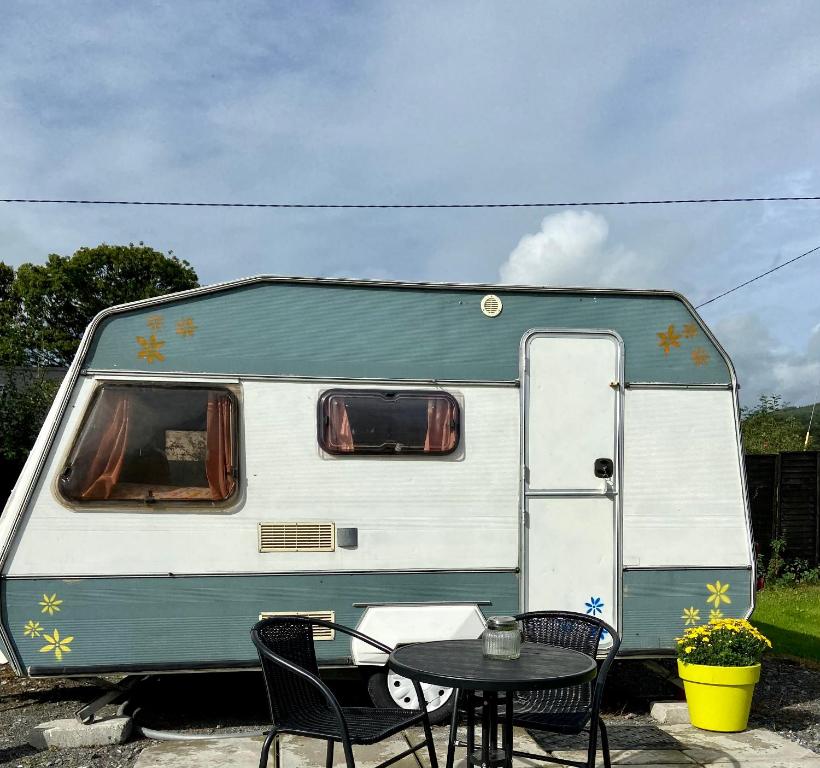 einem grünen und weißen Wohnwagen mit einem Tisch und Stühlen in der Unterkunft Cosy Caravan at Carrigeen Glamping in Kilkenny