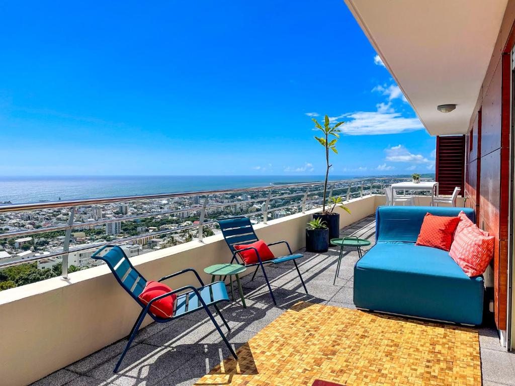 un patio con sedie e un divano sul balcone. di Le Pétrel dans les Nuages - Appartement avec terrasse en plein ciel dominant Saint-Denis a Saint-Denis