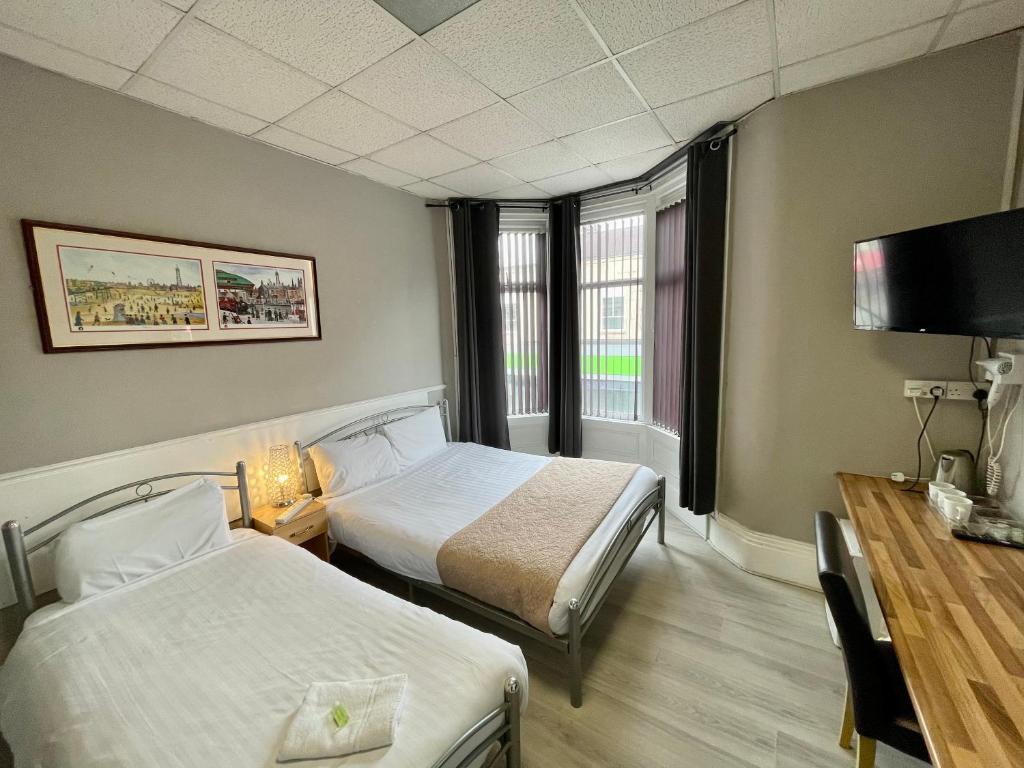 a hotel room with two beds and a television at Topaz Blackpool in Blackpool