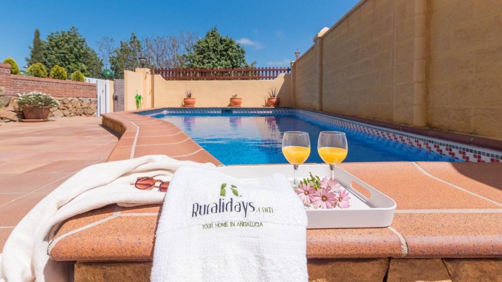 a table with two glasses of wine next to a swimming pool at Casa Sierra Alhaurín de la Torre by Ruralidays in Alhaurín de la Torre