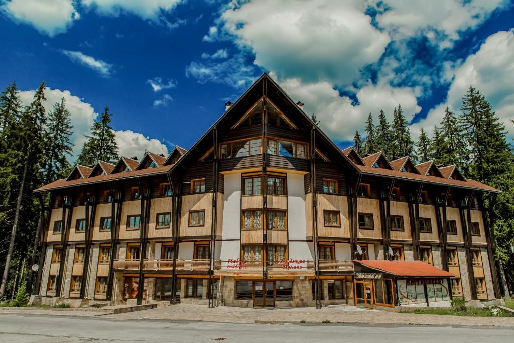 a large building in the mountains with trees at Effect Malina Residence Hotel in Pamporovo