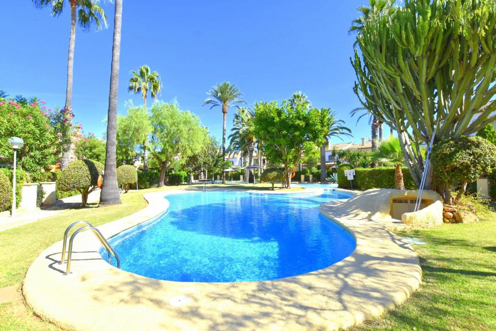 a swimming pool in a resort with palm trees at Casa Rosa Javea in Jávea