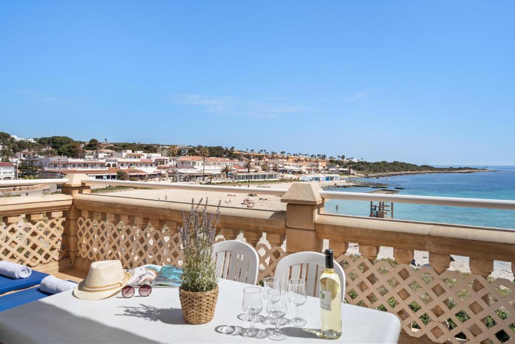 a table with wine glasses and a view of the beach at Punta Prima Apartments in Punta Prima
