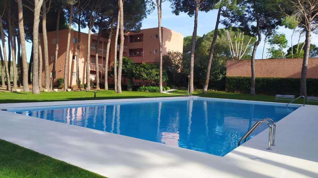 a swimming pool in front of a building with palm trees at Bonito apartamento, con piscina, excelente wifi y aire acondicionado in Pals