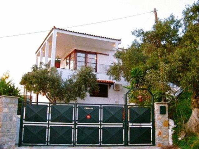 una casa con una puerta verde delante de una casa en Xanemos Villa en Skíathos