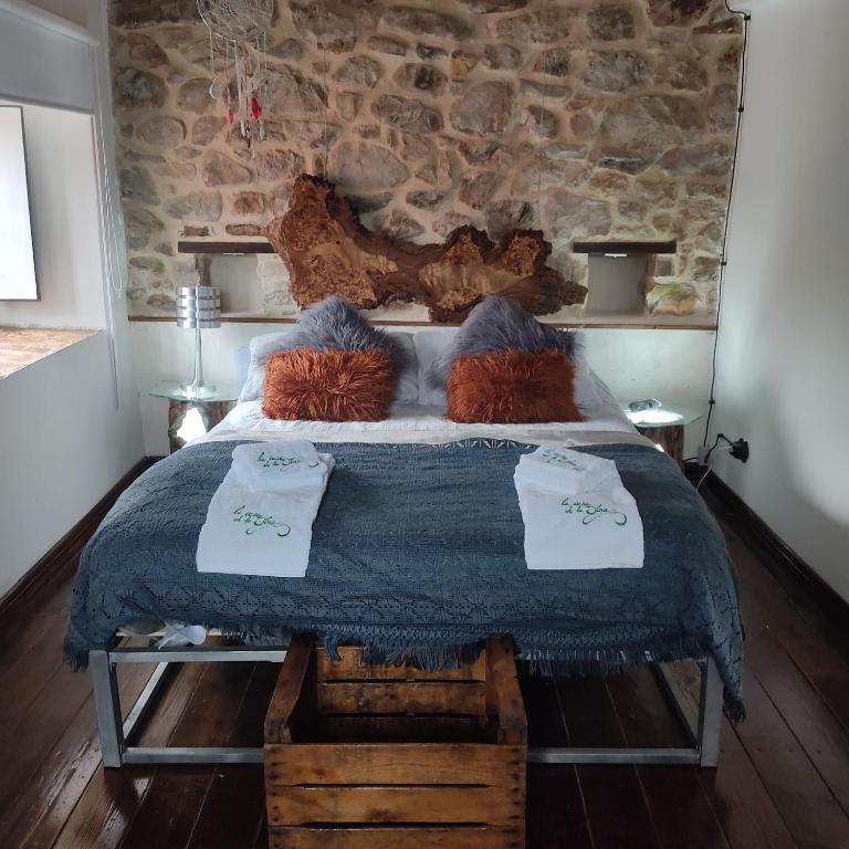 Un dormitorio con una cama grande con una pared de piedra. en La casa de la Tina, en Porquera de Santullán