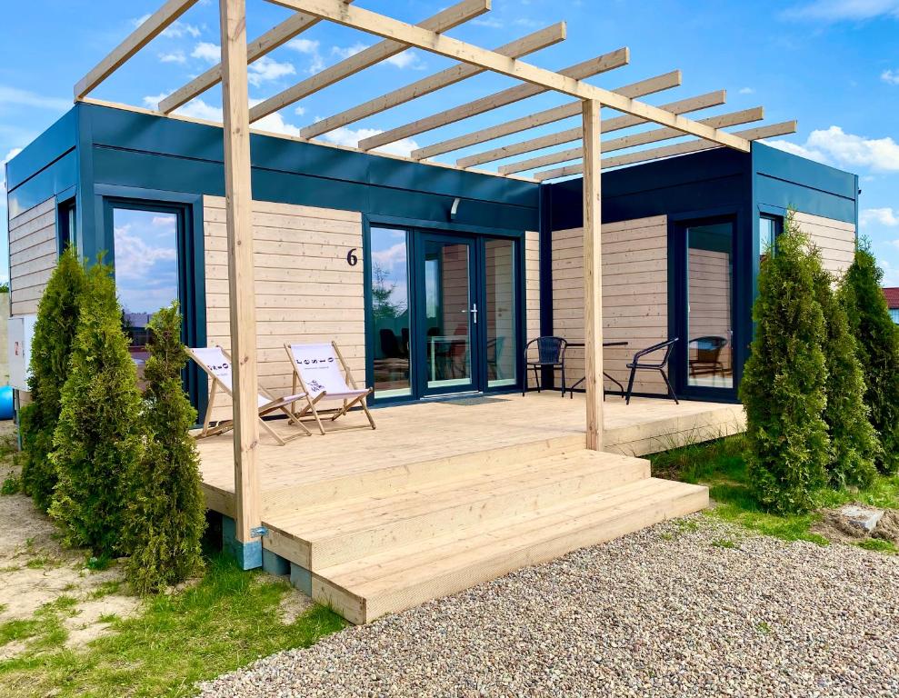 une maison bleue et blanche avec une terrasse en bois dans l'établissement Resto domki letniskowe, à Sarbinowo