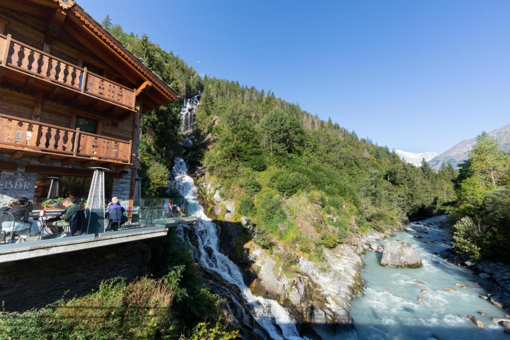 a bridge over a river in front of a building at La Cascata Chambres d'hôtes in La Salle